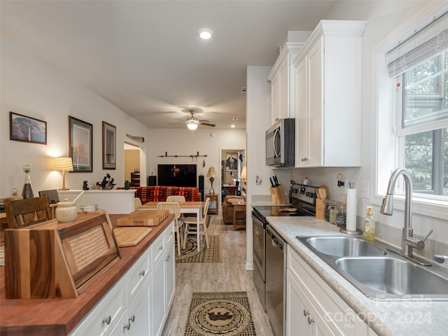 kitchen with white cabinetry, light hardwood / wood-style floors, ceiling fan, stainless steel appliances, and sink