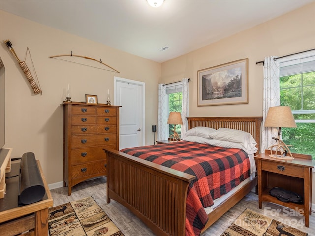 bedroom with light hardwood / wood-style floors and multiple windows