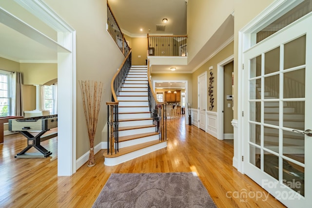 entryway featuring ornate columns, crown molding, and wood-type flooring