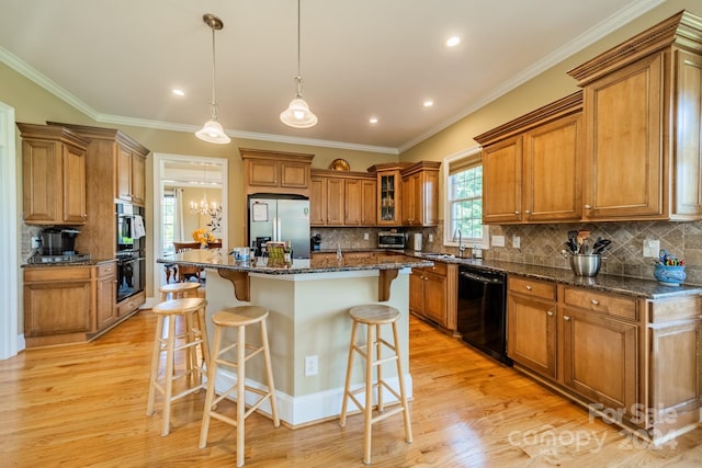 kitchen with a kitchen breakfast bar, a kitchen island, dark stone counters, and black appliances