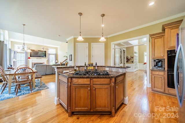 kitchen featuring decorative light fixtures, a kitchen island, dark stone countertops, and black gas cooktop