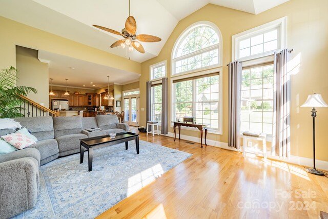 living room with a healthy amount of sunlight, ceiling fan, light hardwood / wood-style floors, and vaulted ceiling