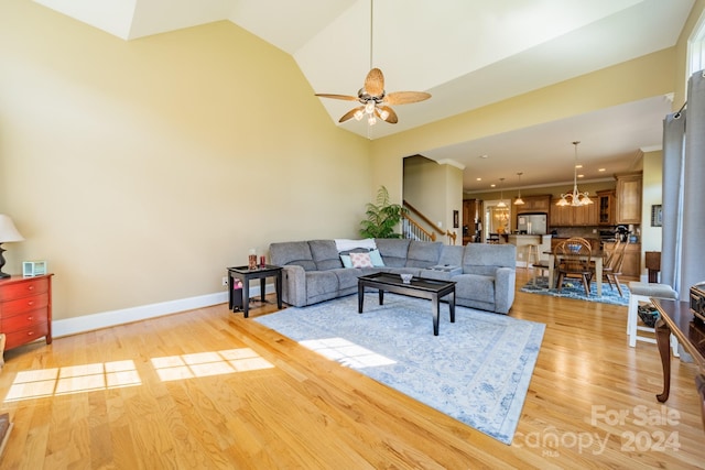 living room with lofted ceiling, light hardwood / wood-style flooring, and ceiling fan with notable chandelier