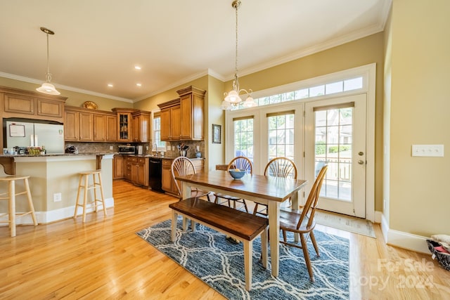 dining area with ornamental molding, a notable chandelier, and light wood-type flooring