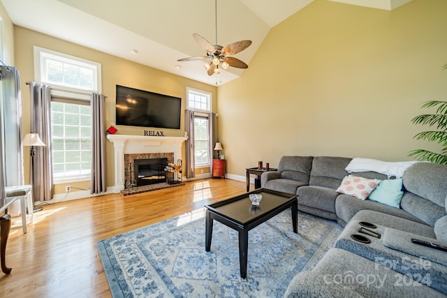 living room with hardwood / wood-style floors, ceiling fan, a high ceiling, and a brick fireplace