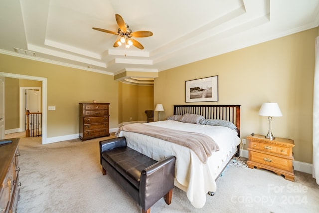 carpeted bedroom with ceiling fan, crown molding, and a tray ceiling