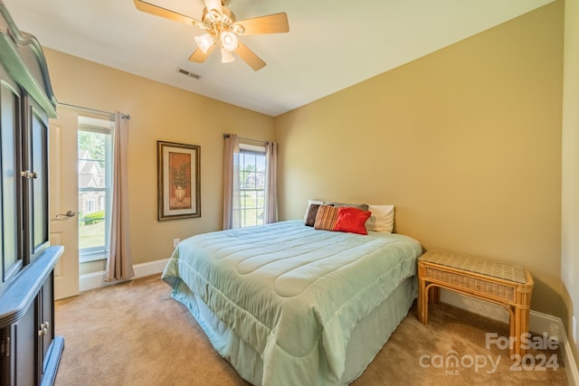 bedroom with multiple windows, ceiling fan, and light carpet