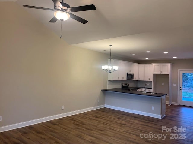 kitchen with dark wood-type flooring, kitchen peninsula, pendant lighting, white cabinets, and appliances with stainless steel finishes