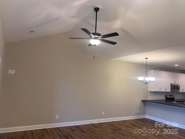 interior space with ceiling fan with notable chandelier, dark hardwood / wood-style flooring, and vaulted ceiling