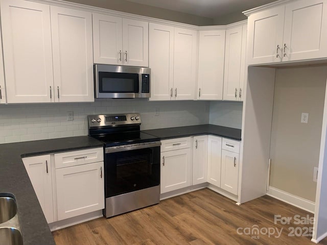 kitchen featuring white cabinetry, sink, decorative backsplash, appliances with stainless steel finishes, and hardwood / wood-style flooring