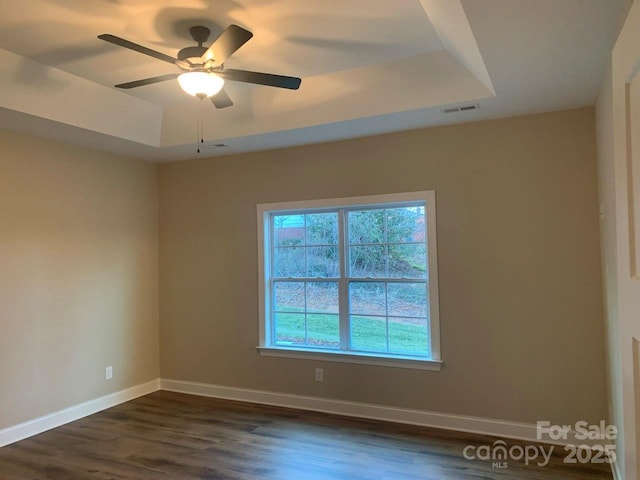 unfurnished room featuring dark hardwood / wood-style flooring, a raised ceiling, and ceiling fan