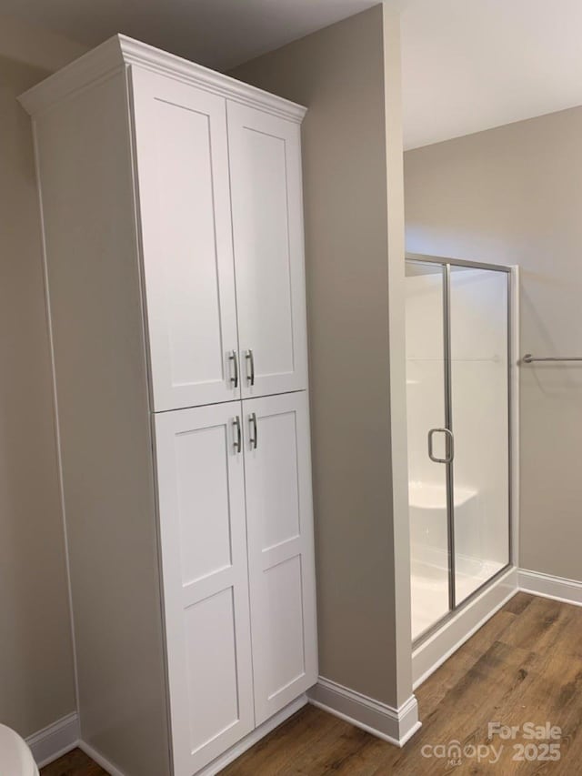 bathroom with hardwood / wood-style flooring and an enclosed shower