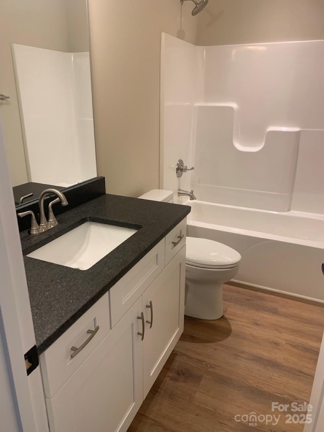 full bathroom featuring hardwood / wood-style flooring, vanity,  shower combination, and toilet