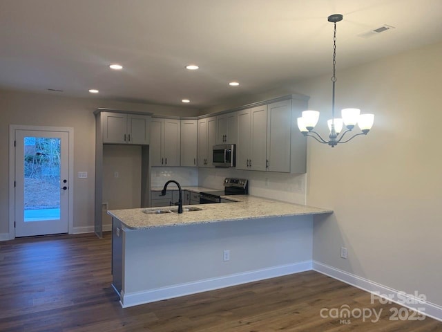 kitchen with sink, dark wood-type flooring, kitchen peninsula, pendant lighting, and appliances with stainless steel finishes