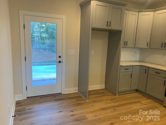 kitchen featuring backsplash, gray cabinetry, and light wood-type flooring