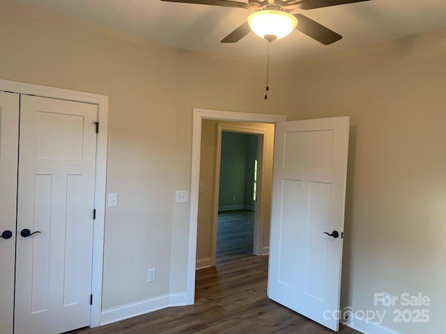 unfurnished bedroom with ceiling fan, dark wood-type flooring, and a closet