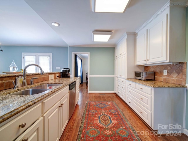 kitchen featuring decorative backsplash, light stone counters, stainless steel dishwasher, sink, and white cabinets