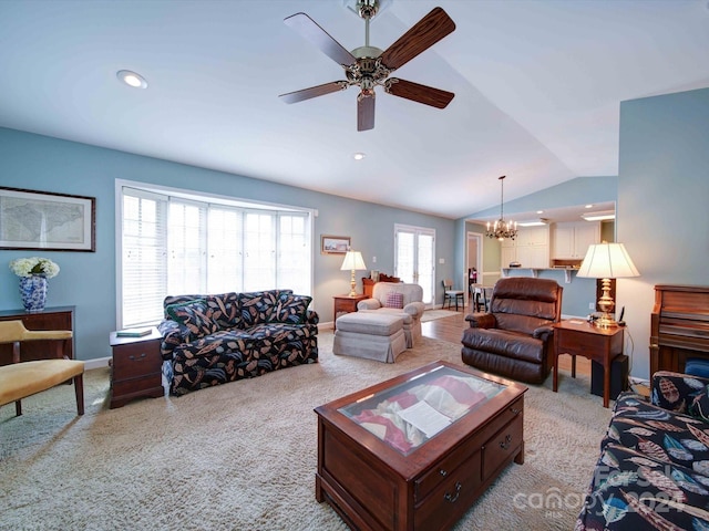 carpeted living room featuring ceiling fan with notable chandelier and vaulted ceiling