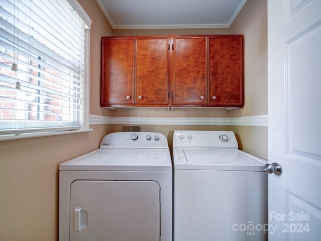 laundry room featuring washing machine and clothes dryer, cabinets, and ornamental molding