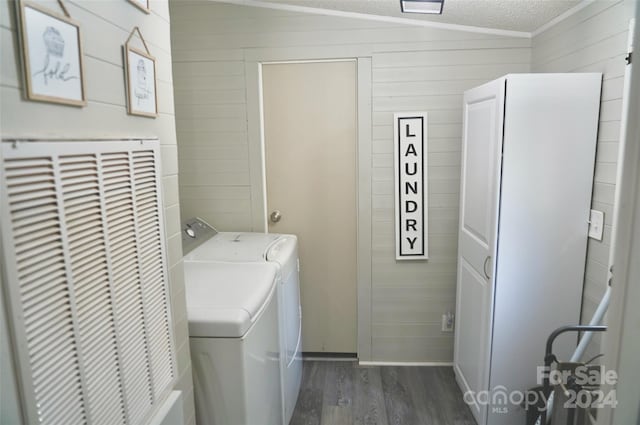 washroom featuring wood walls, washer and dryer, dark hardwood / wood-style floors, a textured ceiling, and cabinets