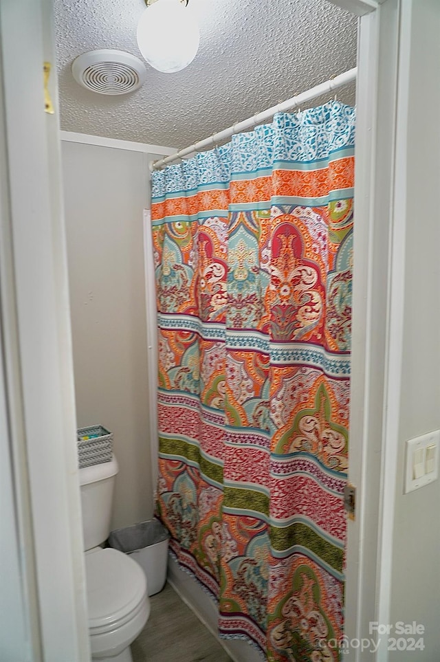 bathroom featuring a textured ceiling, toilet, and a shower with curtain