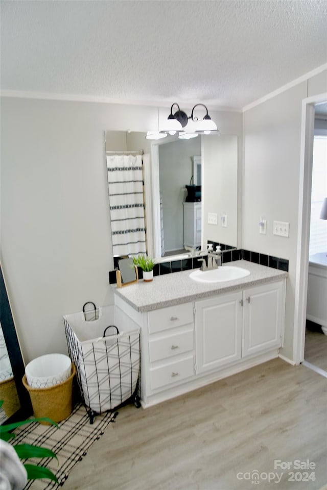 bathroom featuring vanity, hardwood / wood-style floors, a shower with curtain, crown molding, and a textured ceiling