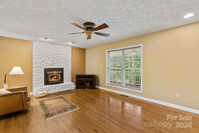 living room with hardwood / wood-style flooring, ceiling fan, and a textured ceiling