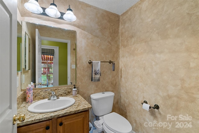 bathroom featuring vanity, toilet, and a textured ceiling