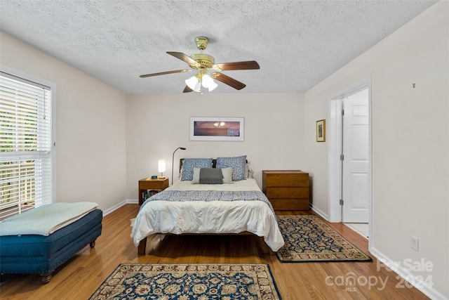 bedroom with ceiling fan, wood-type flooring, and a textured ceiling