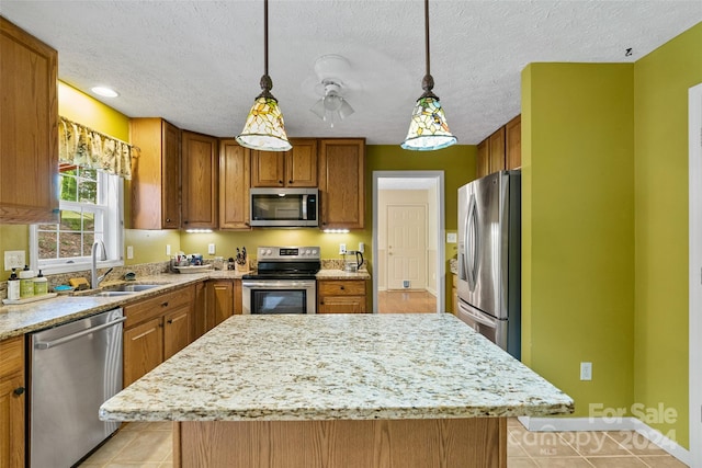 kitchen featuring pendant lighting, stainless steel appliances, a kitchen island, and sink