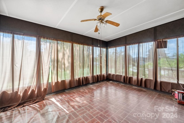 unfurnished sunroom featuring ceiling fan