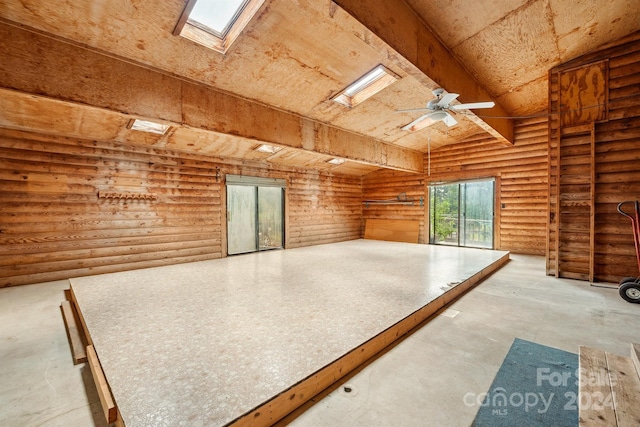 interior space featuring rustic walls, ceiling fan, and lofted ceiling with skylight