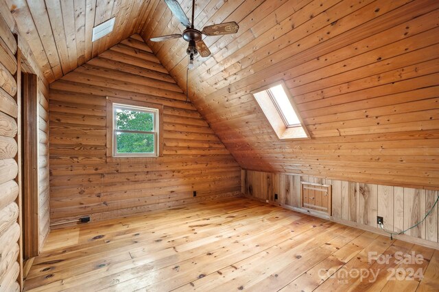 additional living space with ceiling fan, vaulted ceiling with skylight, wood ceiling, and light wood-type flooring