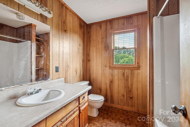 bathroom with parquet flooring, a textured ceiling, toilet, wooden walls, and vanity