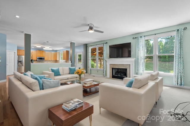 living room with ceiling fan, light wood-type flooring, and a fireplace