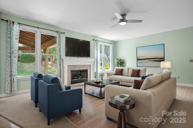 living room featuring a wealth of natural light, light hardwood / wood-style flooring, and a tiled fireplace