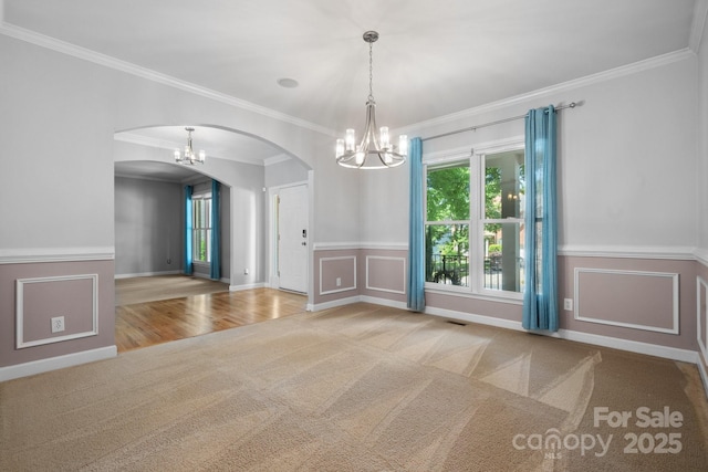 carpeted empty room featuring an inviting chandelier and crown molding