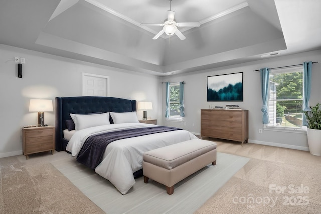 bedroom featuring ceiling fan, multiple windows, and a tray ceiling