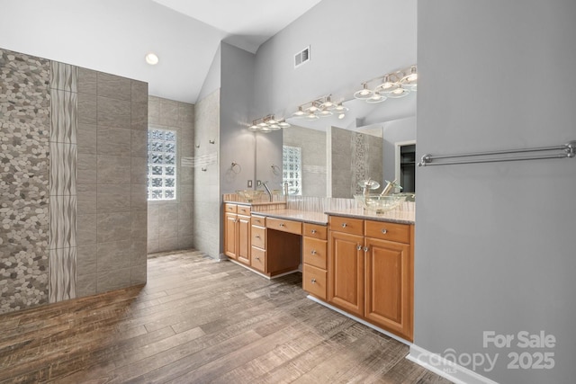 bathroom featuring a shower, lofted ceiling, hardwood / wood-style flooring, and vanity