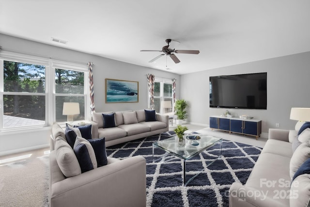 living room featuring dark colored carpet, a healthy amount of sunlight, and ceiling fan