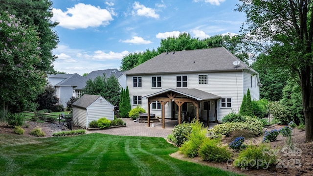 rear view of property featuring a patio, a lawn, and a shed