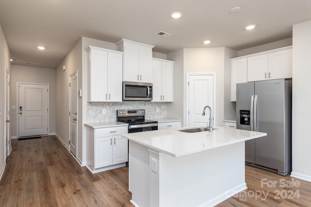 kitchen with white cabinetry, light hardwood / wood-style flooring, an island with sink, and appliances with stainless steel finishes