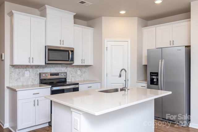 kitchen with white cabinets, stainless steel appliances, a kitchen island with sink, and sink