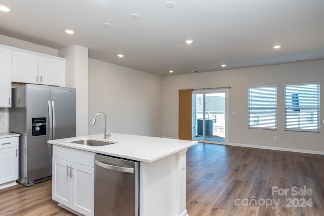 kitchen with stainless steel appliances, sink, wood-type flooring, white cabinets, and an island with sink