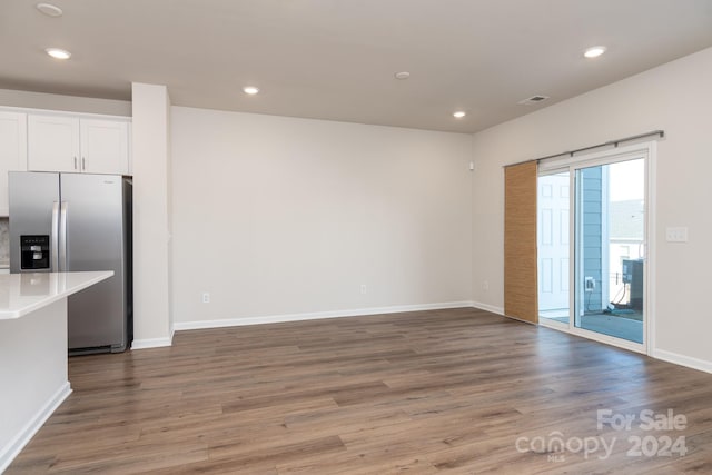 interior space featuring stainless steel fridge, white cabinets, and hardwood / wood-style flooring