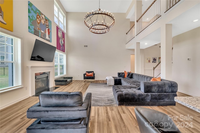 living room featuring wood-type flooring, a towering ceiling, and a notable chandelier