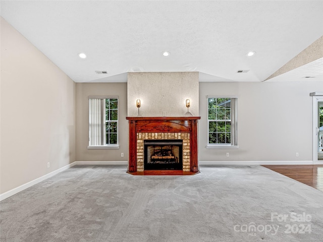 unfurnished living room featuring a healthy amount of sunlight, carpet flooring, and lofted ceiling