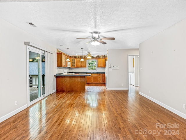 kitchen featuring a textured ceiling, ceiling fan, decorative light fixtures, light wood-type flooring, and kitchen peninsula