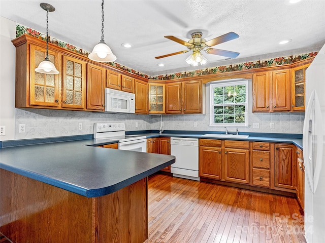 kitchen featuring white appliances, dark wood-type flooring, pendant lighting, backsplash, and sink