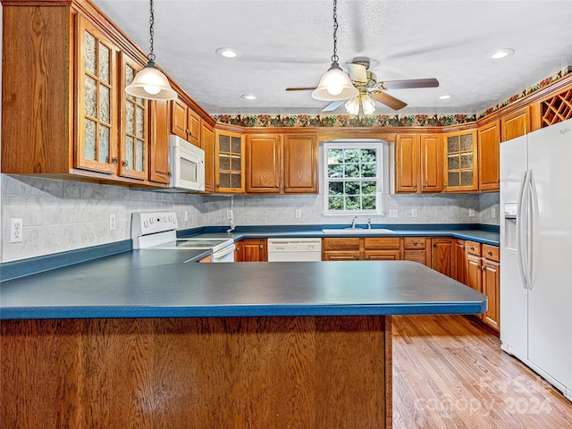 kitchen with tasteful backsplash, white appliances, pendant lighting, sink, and kitchen peninsula